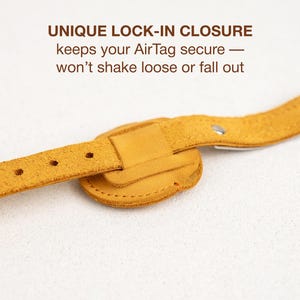 Op de afbeelding: Mosterdgele leren band met een unieke lock-in sluiting ontworpen om een AirTag te beveiligen. De tekst "UNIQUE LOCK-IN CLOSURE keeps your AirTag secure &mdash; won't shake loose or fall out" is zichtbaar. De band heeft een getextureerd oppervlak.