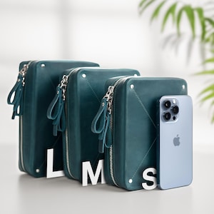 May include: Three teal leather zippered pouches with a teal leather phone case and a silver iPhone with a black camera lens. The pouches are labeled L, M, and S.
