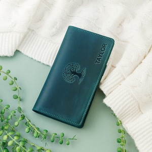 May include: Teal leather wallet with a tree design and the name "TAYLOR" embossed on the front.