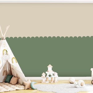 Puede incluir: Un cuarto de juegos infantil con una tienda tipi, bloques de madera y un cochecito de juguete. Las paredes están pintadas en dos tonos: beige claro en la parte superior y verde salvia en la inferior, separados por un borde festoneado. Una alfombra pequeña y cojines decorativos completan la escena.