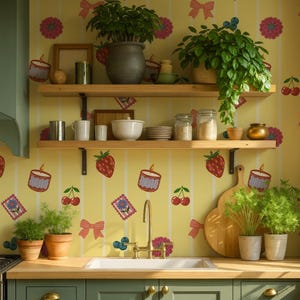 May include: A kitchen interior with green cabinets, a wooden worktop, and a white sink. Two wooden shelves display kitchenware and potted plants. The yellow wallpaper is patterned with strawberries, cherries, and floral motifs.