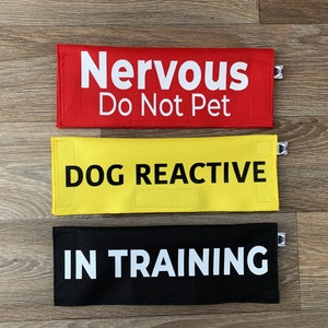 Peut inclure: Trois panneaux d'avertissement pour l'entraînement des chiens. Le panneau du haut est rouge avec du texte blanc qui dit "Nervoso Ne pas caresser". Le panneau du milieu est jaune avec du texte noir qui dit "Chien réactif". Le panneau du bas est noir avec du texte blanc qui dit "En formation".