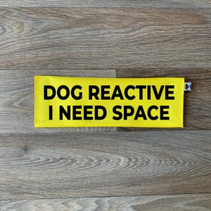 May include: Yellow dog lead with black text that reads "DOG REACTIVE I NEED SPACE".