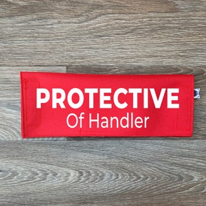 May include: Red fabric pouch with white text that reads "PROTECTIVE Of Handler".