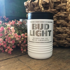 May include: White insulated beverage holder with a black lid. The holder has a silver sticker with the text "Bud Light" and "Brewed for the Best Grandpa".