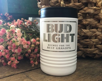 May include: White insulated beverage holder with a black lid. The holder has a silver sticker with the text "Bud Light" and "Brewed for the Best Grandpa".