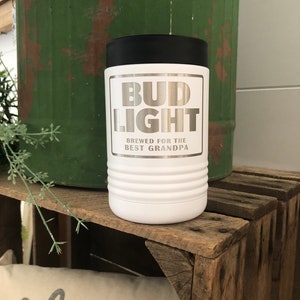 May include: White stainless steel can cooler with a black lid. The cooler has a silver Bud Light logo with the text "Brewed for the Best Grandpa".