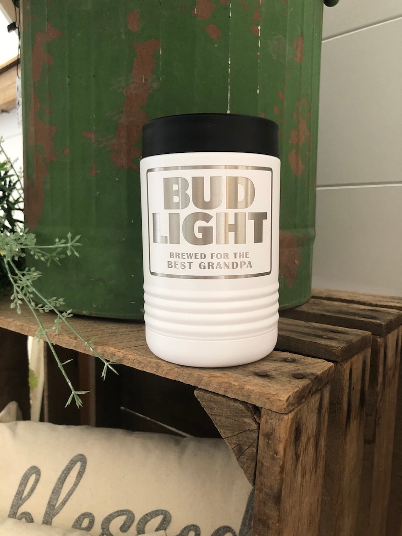 May include: White stainless steel can cooler with a black lid. The cooler has a silver Bud Light logo with the text "Brewed for the Best Grandpa".