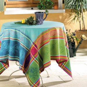May include: A colorful tablecloth with a green, blue, and orange plaid pattern. The tablecloth is made of cotton and has a woven texture. It is laid out on a table with a metal base.