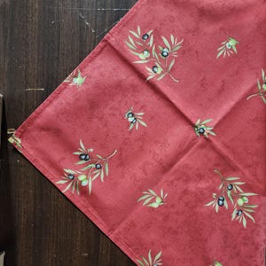 May include: Red fabric with a pattern of green olive branches and black olives.