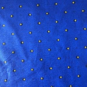 Puede incluir: Primer plano de una tela azul con un patrón repetido de pequeños diseños florales amarillos y negros. La tela tiene un aspecto ligeramente texturizado, con el patrón floral espaciado uniformemente.