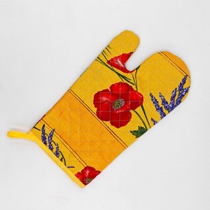May include: Yellow quilted oven mitt with a floral design featuring red poppies and blue lavender sprigs. The mitt has a loop for hanging and is designed for kitchen use.