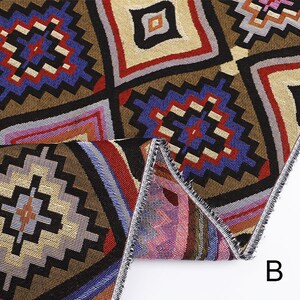 Peut inclure: Gros plan sur un tissu color&eacute; avec un motif g&eacute;om&eacute;trique. Le tissu est brun, rouge, bleu et blanc. Le tissu est pli&eacute; en deux et les bords sont visibles. La lettre "B" est visible dans le coin inf&eacute;rieur droit de l'image.