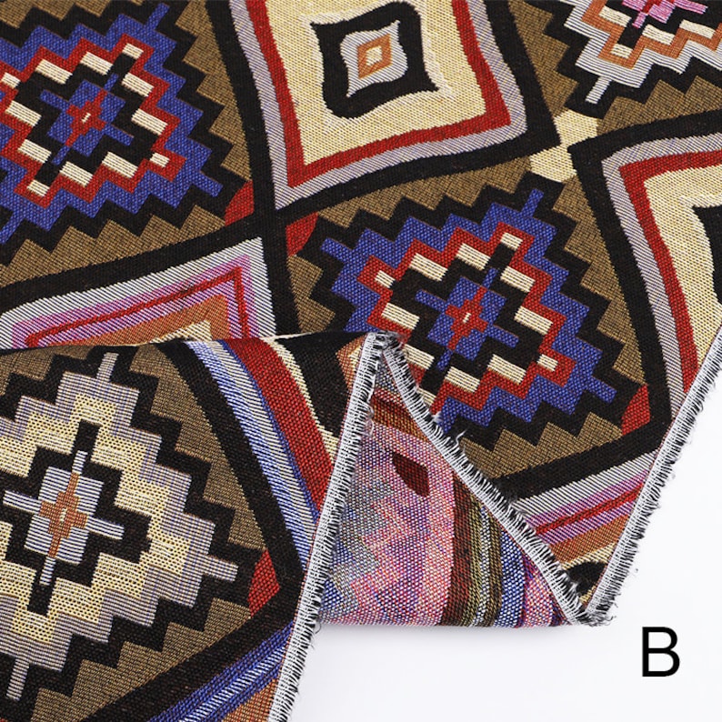 Peut inclure: Gros plan sur un tissu color&eacute; avec un motif g&eacute;om&eacute;trique. Le tissu est brun, rouge, bleu et blanc. Le tissu est pli&eacute; en deux et les bords sont visibles. La lettre "B" est visible dans le coin inf&eacute;rieur droit de l'image.