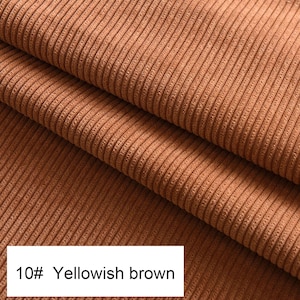 May include: A folded piece of yellowish brown corduroy fabric featuring a distinct vertical ribbed texture. A white rectangular label in the bottom left corner displays the text 10# Yellowish brown in a clear black sans-serif font.