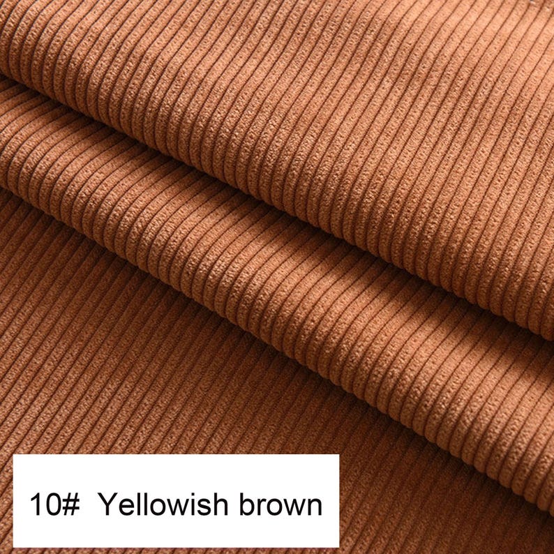 May include: A folded piece of yellowish brown corduroy fabric featuring a distinct vertical ribbed texture. A white rectangular label in the bottom left corner displays the text 10# Yellowish brown in a clear black sans-serif font.