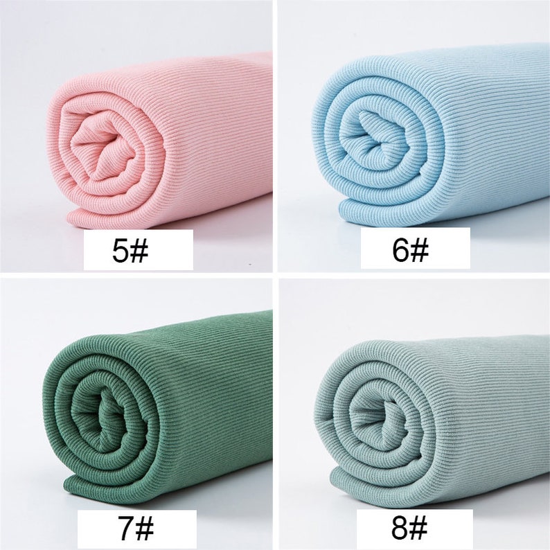 May include: Four rolls of ribbed fabric in various colors: pink, light blue, green, and gray-green. Each roll is labeled with a number. The fabric is tightly rolled, showcasing the texture and color variations. Ideal for sewing and crafting projects.