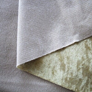 Puede incluir: Primer plano de dos muestras de tela. La muestra superior es de color beige claro y tiene una textura lisa. La muestra inferior es de color verde claro y tiene una textura aterciopelada.