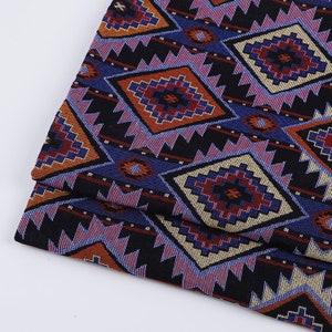 Peut inclure: Gros plan sur un tissu avec un motif g&eacute;om&eacute;trique color&eacute;. Le motif pr&eacute;sente un m&eacute;lange de couleurs bleues, rouges, oranges et jaunes. Le tissu a une texture tiss&eacute;e.