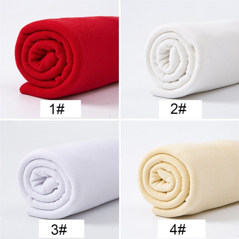 May include: Four rolls of ribbed fabric in different colors. The colors are red, white, off-white, and beige. Each roll is labeled with a number. The fabric is tightly rolled, showing the texture of the material.