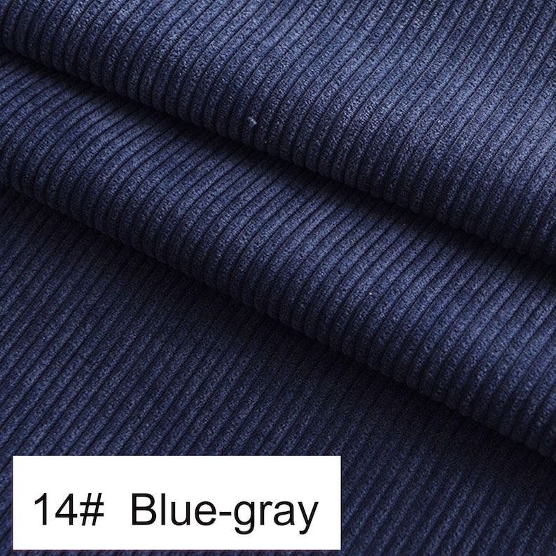May include: A dark blue-gray corduroy fabric featuring a distinct vertical ribbed texture. The material is folded into multiple layers, creating deep shadows and highlights along the ridges. A white label at the bottom displays the text 14# Blue-gray.