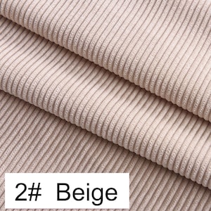 May include: A beige corduroy fabric featuring a distinct vertical ribbed texture with parallel lines running across the surface. A white rectangular label in the bottom left corner displays the black text 2# Beige, identifying the color.