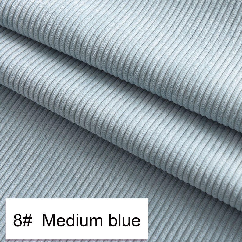May include: A light blue corduroy fabric featuring a distinct vertical ribbed texture. The material is folded into three layers, showcasing the consistent weave and soft appearance of the textile. A white label displays the text 8# Medium blue.