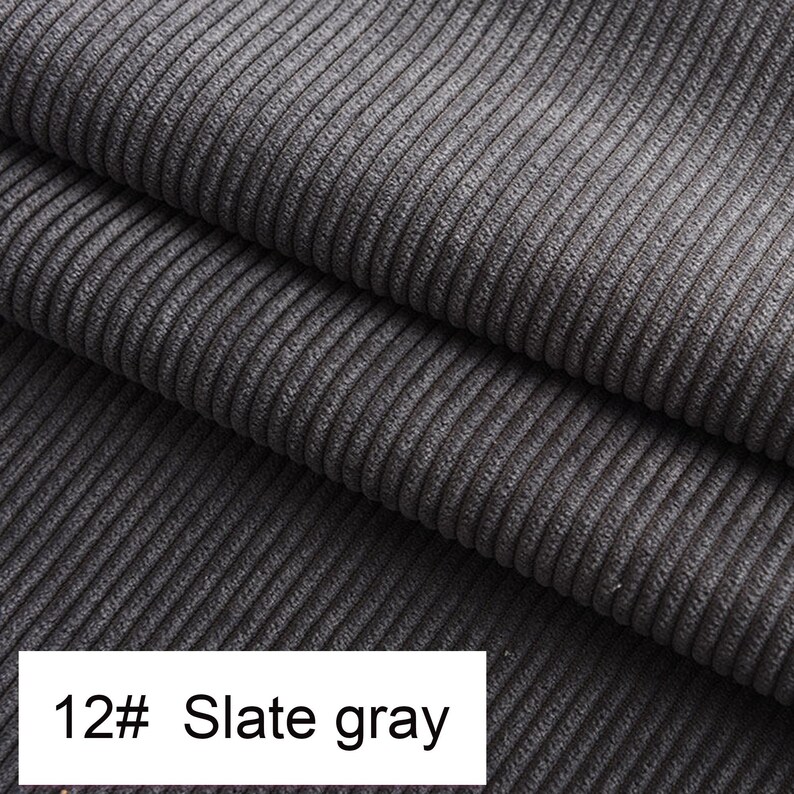 May include: A slate gray corduroy fabric featuring a distinct vertical ribbed texture. The material is folded into multiple layers, showcasing the consistent parallel lines of the weave. A white label at the bottom displays the text 12# Slate gray.