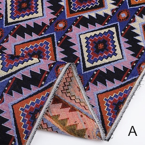 Peut inclure: Gros plan sur un tissu avec un motif g&eacute;om&eacute;trique dans des tons de bleu, rouge, orange et noir. Le tissu a une texture tiss&eacute;e et est pli&eacute; en deux, r&eacute;v&eacute;lant le bord de l'ourlet.
