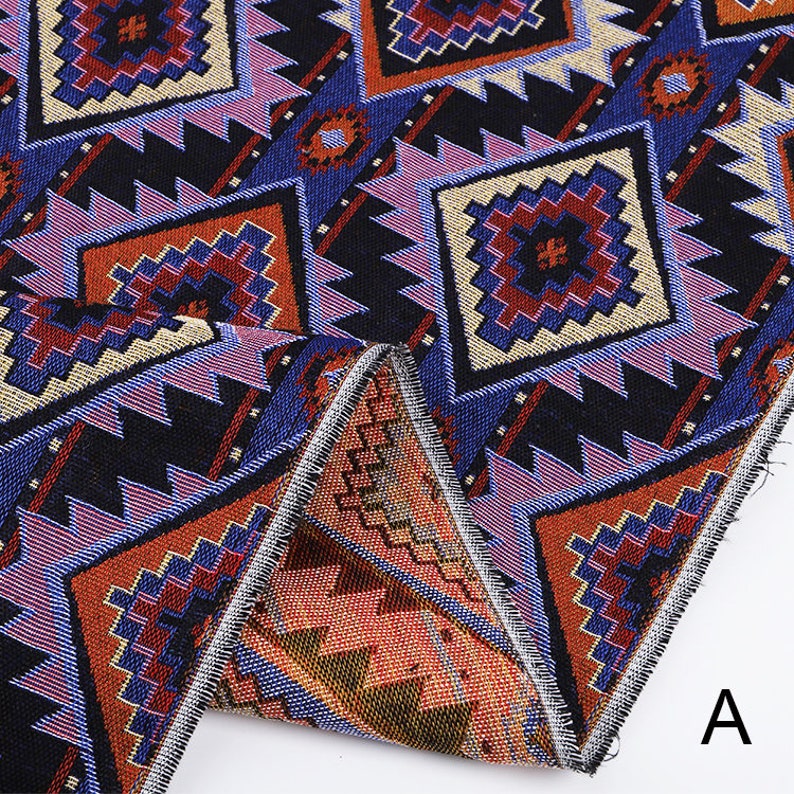 Peut inclure: Gros plan sur un tissu avec un motif g&eacute;om&eacute;trique dans des tons de bleu, rouge, orange et noir. Le tissu a une texture tiss&eacute;e et est pli&eacute; en deux, r&eacute;v&eacute;lant le bord de l'ourlet.
