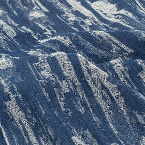 May include: A blue fabric with a white textured pattern. The fabric has a slightly distressed look.
