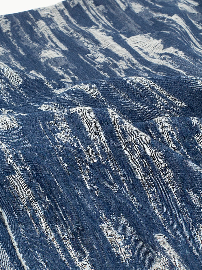 May include: A blue fabric with a white textured pattern. The fabric has a slightly distressed look.