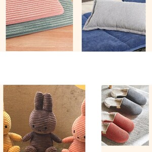 May include: Three corduroy plush bunny toys in different colors: yellow, brown, and pink. The toys are sitting on a wooden surface.