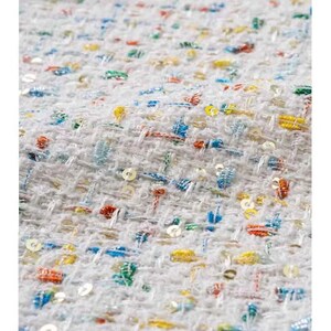 May include: White fabric with a woven texture and colorful sequins. The fabric has a subtle pattern of small squares.