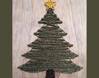May include: A green string art Christmas tree with a yellow star on top. The tree is made of string wrapped around nails hammered into a wooden board.