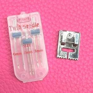May include: A clear plastic case containing three twin needles for a sewing machine. The needles are labelled with sizes 4mm, 2mm, and 3mm. A silver sewing machine foot is also pictured.