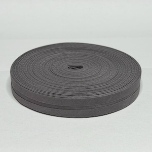 May include: A roll of gray bias tape, neatly coiled. The tape has a smooth, matte finish and is likely made of fabric. The edges are slightly rounded, and the tape appears to be unworn. Ideal for sewing and crafting projects.
