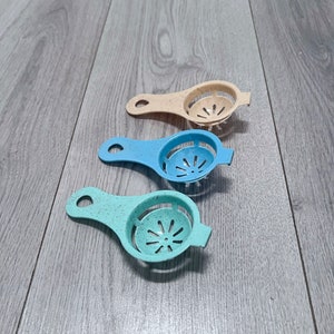 May include: Three egg separators in different colors: beige, blue, and light blue. Each separator has a handle and a strainer with small holes.