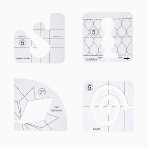 May include: Four white plastic quilting templates with different designs: heart border, bubbles, fan diamond, and swirl. Each template has a number 5 and a line indicating the center. The fan diamond template also has a 7 inch measurement.