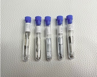May include: Five clear plastic tubes with blue caps containing silver needles. The tubes are labeled with the text "HAX1" and a number. The numbers are 65/9, 11/51, 62/14, 100/76, and 10/18.