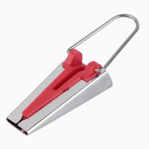 May include: A silver sewing tool with a red plastic handle and a wire loop. The tool is used to create a seam allowance when sewing.