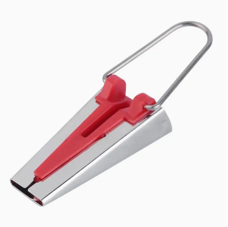 May include: A silver sewing tool with a red plastic handle and a wire loop. The tool is used to create a seam allowance when sewing.