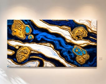 Puede incluir: Una pieza de arte mural rectangular que presenta un diseño fluido abstracto con patrones de remolinos en azul profundo, blanco y dorado. La composición incluye elementos circulares dorados y turquesas en relieve y texturizados.