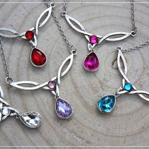 Può includere: Cinque collane d'argento con ciondoli di cristallo a forma di goccia. Le collane presentano un design a nodo celtico e sono disponibili in una varietà di colori, tra cui rosso, rosa, viola, blu e trasparente.