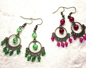 May include: A pair of dangle earrings with a bronze filigree design. One pair features green glass beads and the other pair features pink glass beads.