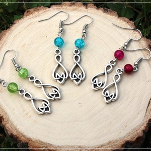 May include: Three pairs of dangle earrings with silver Celtic knot charms. The earrings feature green, blue, and red glass beads.
