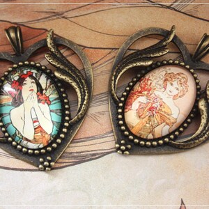 Peut inclure: Deux pendentifs antiques de couleur bronze. Chaque pendentif présente une image ovale d'une femme de style Art nouveau, entourée d'une bordure perlée. Les pendentifs ont un cadre en forme de cœur avec des accents de feuilles décoratives.