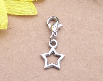 Könnte beinhalten: Ein silberfarbener Metallanhänger in Form eines fünfzackigen Sterns mit offener Mitte. Der Stern ist mit einem runden Biegering an einem kleinen silberfarbenen Karabinerverschluss befestigt, was ein funktionales Teil für Schmuck oder Accessoires ergibt.