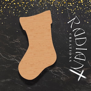 May include: A wooden cutout of a Christmas stocking in a light brown color. The stocking is on a black background with gold glitter.