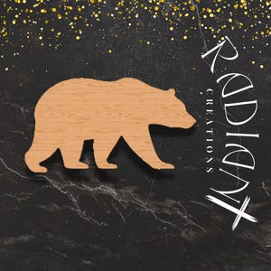 Könnte beinhalten: Hellbraune Holz-Bär-Silhouette. Der Bär geht nach links. Schwarzer Hintergrund mit goldenem Glitzer und weißem Text "Radiant Creations".